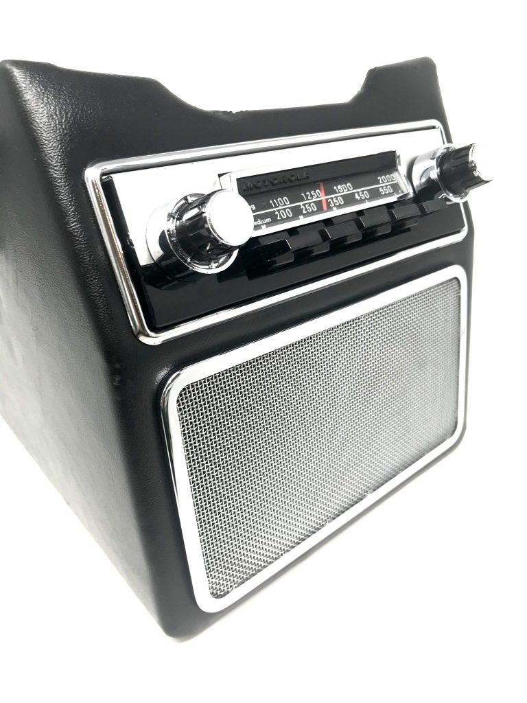 Aston Martin DB6 radio console showing restored Motorola 727 radio and chrome speaker grille